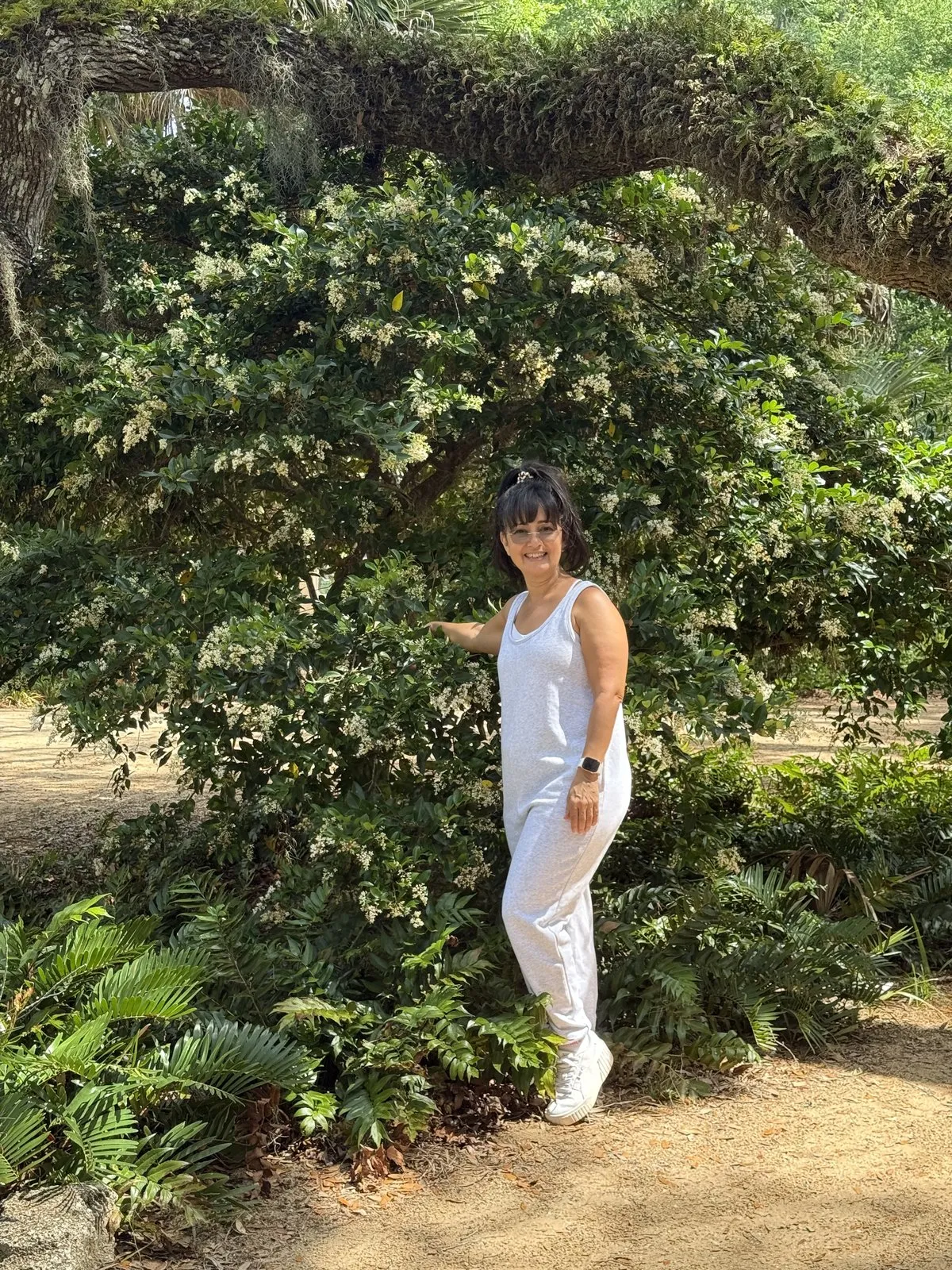 Marlene Falcón junto a un árbol florido en el jardín